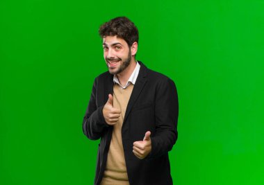 Genç iş adamı kendini mutlu, sakin, rahat ve başarılı hisseder. Kameraya bakar, yeşil arka plana karşı seni seçer.