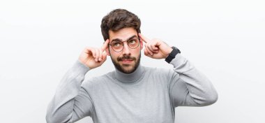 Genç yönetici, kafası karışık ya da şüpheci hissediyor, bir fikre odaklanıyor, çok düşünüyor, beyaz duvara karşı boşluğu kopyalamak istiyor.