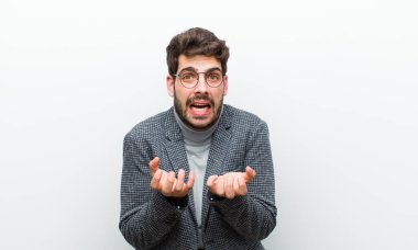 Genç yönetici umutsuz ve sinirli görünüyor, stresli, mutsuz ve sinirli, beyaz duvara karşı bağırıyor ve çığlık atıyor.