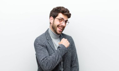 Genç yönetici mutlu, pozitif ve başarılı hissediyor, meydan okumayla karşılaştığında motive oluyor veya beyaz duvara karşı iyi sonuçları kutluyor.