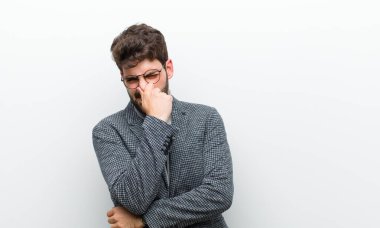 Genç müdür, beyaz duvardaki pis ve nahoş kokuyu koklamamak için burnunu tutuyor.