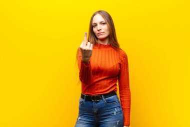 Genç, güzel bir kadın kızgın, sinirli, isyankar ve agresif hissediyor. Orta parmağıyla turuncu arka plana karşı koyuyor.