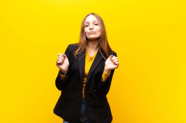 Genç, güzel iş kadını dudaklarını birbirine bastırıyor, tatlı, eğlenceli, mutlu, sevimli bir yüz ifadesiyle, turuncu arka plana öpücük yolluyor.