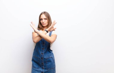 Genç ve güzel bir kadın senin bu tavırlarından rahatsız ve bıkkın görünüyor. Yeter artık! Eller önde çapraz, beyaz duvara karşı durmanı söylüyor.