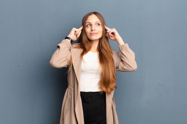 Genç, güzel bir kadın, kafası karışmış ya da şüpheye düşmüş, bir fikre odaklanmış, çok düşünüyor, gri arka plana uzayı kopyalamak istiyor.