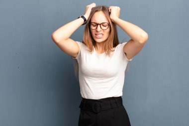 Genç, güzel bir kadın stresli ve hayal kırıklığına uğramış hissediyor. El ele tutuşuyor. Yorgun, mutsuz ve migreni gri arka planda.