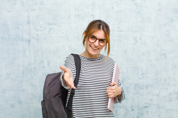 若い学生の女性は笑顔で 幸せそうに 自信があり 友好的で 取引を終わらせるための握手を提供し グランジウォールの背景に対して協力します — ストック写真