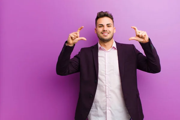 young hispanic man framing or outlining own smile with both hands, looking positive and happy, wellness concept