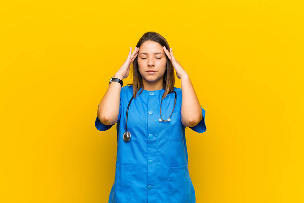 looking concentrated, thoughtful and inspired, brainstorming and imagining with hands on forehead isolated against yellow wall
