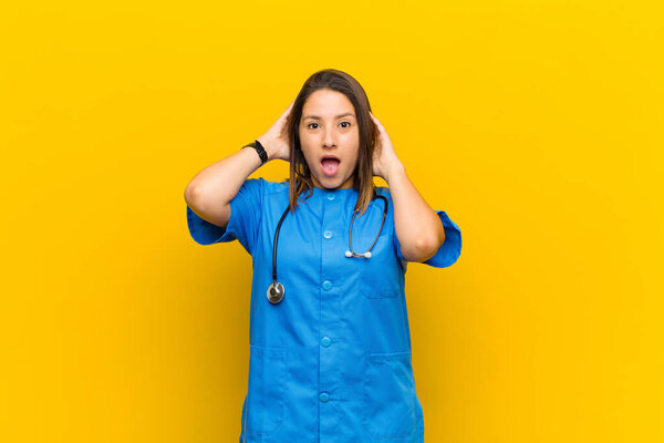 feeling stressed, worried, anxious or scared, with hands on head, panicking at mistake isolated against yellow wall