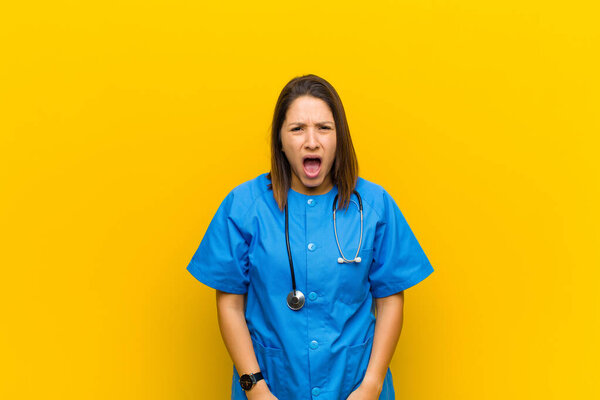 looking shocked, angry, annoyed or disappointed, open mouthed and furious isolated against yellow wall