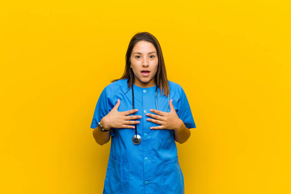 looking happy, surprised, proud and excited, pointing to self isolated against yellow wall