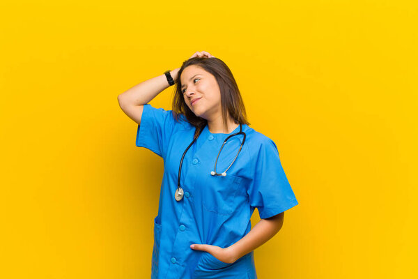 smiling cheerfully and casually, taking hand to head with a positive, happy and confident look isolated against yellow wall