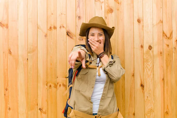 young latin explorer woman against wooden wall background