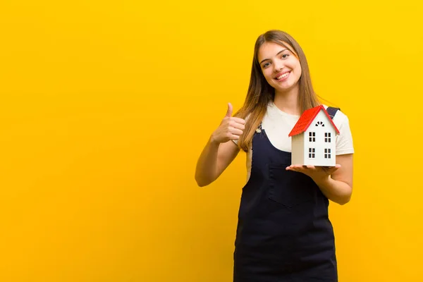 Jong Mooi Vrouw Met Een Huis Model Tegen Oranje Achtergrond — Stockfoto