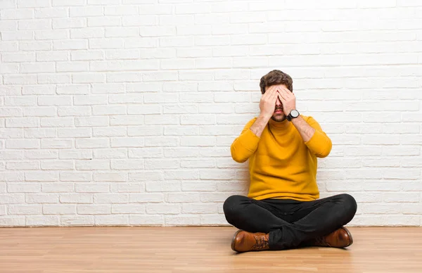 Joven Hombre Guapo Sentado Suelo Casa Contra Textura Pared Ladrillo —  Fotos de Stock