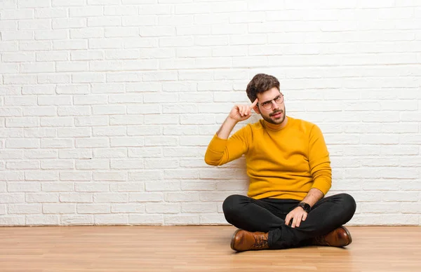 Joven Hombre Guapo Sentado Suelo Casa Contra Textura Pared Ladrillo —  Fotos de Stock