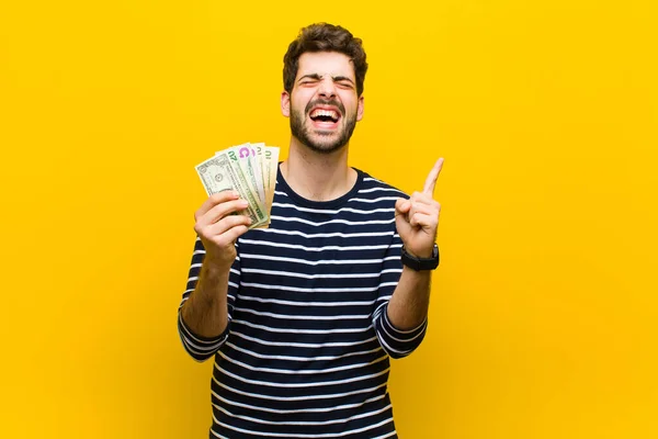 Joven hombre guapo con billetes de dólar contra fondo naranja — Foto de Stock