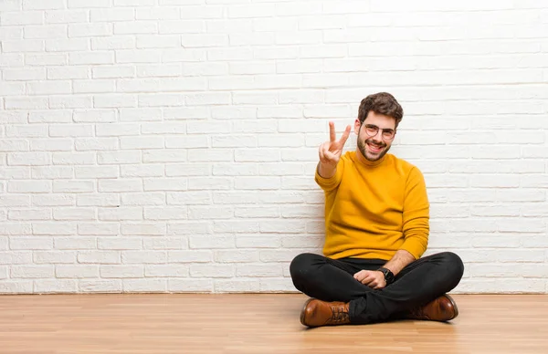 Junger Gutaussehender Mann Sitzt Auf Dem Fußboden Vor Einer Ziegelwand — Stockfoto