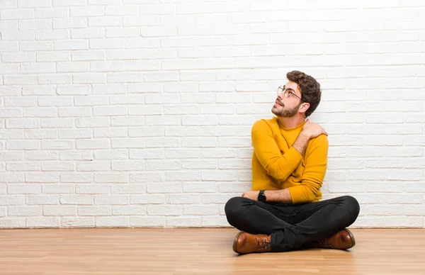 Joven Hombre Guapo Sentado Suelo Casa Contra Textura Pared Ladrillo —  Fotos de Stock