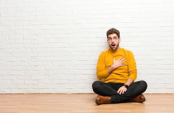 Joven Hombre Guapo Sentado Suelo Casa Contra Textura Pared Ladrillo — Foto de Stock