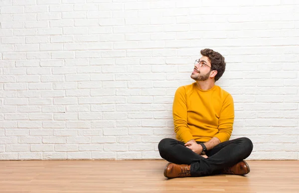 Junger Gutaussehender Mann Sitzt Auf Dem Fußboden Vor Einer Ziegelwand — Stockfoto