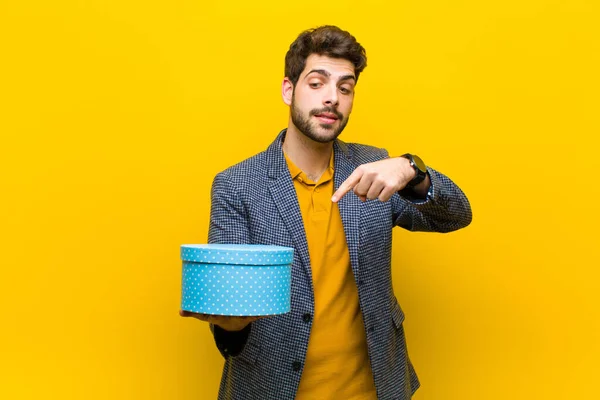 Jovem homem bonito com uma caixa contra fundo laranja — Fotografia de Stock