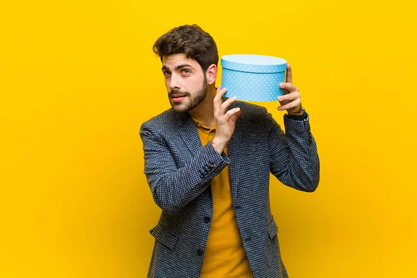 Jovem homem bonito com uma caixa contra fundo laranja — Fotografia de Stock