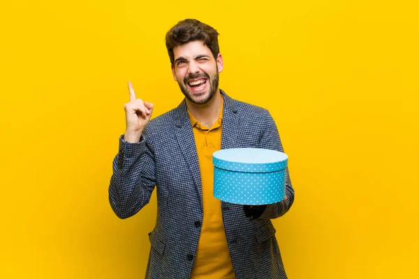 Jovem homem bonito com uma caixa contra fundo laranja — Fotografia de Stock