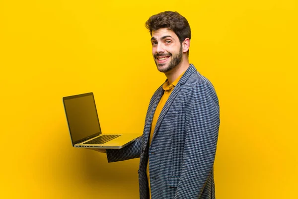Jovem homem bonito com um laptop contra fundo laranja — Fotografia de Stock