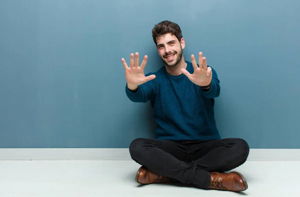 Young Handsome Man Sitting Floor Smiling Looking Friendly Showing Number — 图库照片