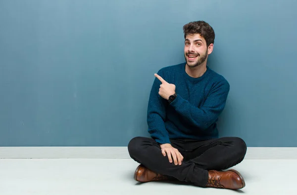 Giovane Bell Uomo Seduto Sul Pavimento Guardando Eccitato Sorpreso Indicando — Foto Stock