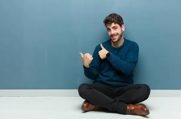 Jovem Homem Bonito Sentado Chão Sorrindo Alegre Casualmente Apontando Para — Fotografia de Stock