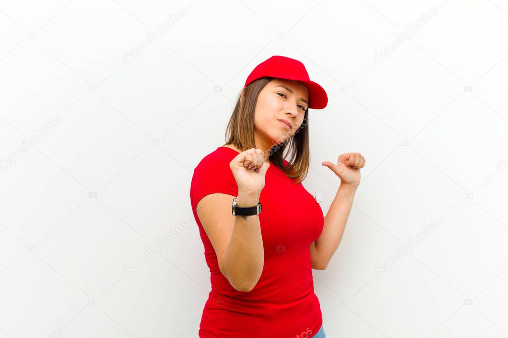 delivery woman feeling proud, arrogant and confident, looking satisfied and successful, pointing to self against white background