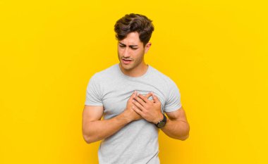  Üzgün, yaralı ve kalbi kırık görünüyor, iki elini de kalbe yakın tutuyor, ağlıyor ve depresif hissediyor.