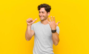  Gülümsüyor ve arkadaş canlısı görünüyor, altı ya da altıncı numarayı gösteriyor, elleri önde, geri sayıyor.