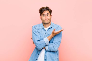 Genç, yakışıklı bir adam, kafası karışık ve bilgisiz, şüpheli bir açıklamayı merak ediyor ya da pembe arka plana karşı düşünce