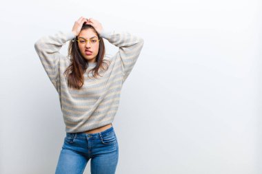 Genç ve güzel bir kadın hayal kırıklığına uğramış ve sıkılmış hissediyor, başarısızlıktan bıkmış ve bıkmış, sıkıcı işlerden bıkmış, beyaz duvara yaslanmış.