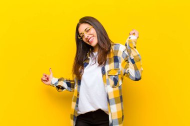 Genç, güzel bir kadın gülümsüyor, kaygısız, rahat ve mutlu hissediyor, dans ediyor ve müzik dinliyor, turuncu duvarın karşısındaki bir partide eğleniyor.