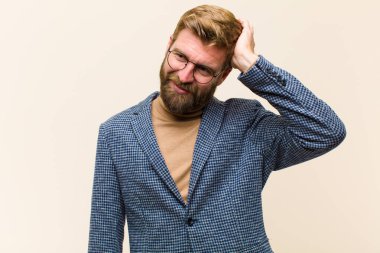 Genç sarışın iş adamı neşeli ve sıradan bir şekilde gülümsüyor, olumlu, mutlu ve kendinden emin bir bakışla göğüs göğüse tutuşuyor.