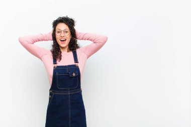 Genç, güzel bir kadın mutlu, kaygısız, arkadaş canlısı ve rahat görünüyor. Hayattan ve başarıdan keyif alıyor, beyaz duvara karşı pozitif bir tutum sergiliyor.