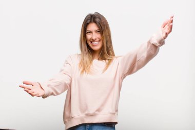 Genç, güzel bir kadın neşeyle gülümsüyor, samimi, sevgi dolu bir kucaklama yapıyor, beyaz arka plana karşı mutlu ve sevimli hissediyor.