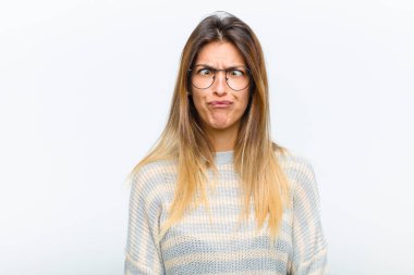 Genç ve güzel bir kadın şapşal ve komik görünüyor. Aptal şaşı bir ifadeyle, şaka yapıyor ve beyaz arka planda takılıyor.