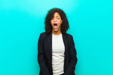 Genç siyahi kadın agresif bir şekilde bağırıyor, kızgın, sinirli, öfkeli ya da sinirli görünüyor, mavi duvara karşı hayır diye bağırıyor.