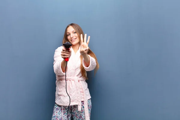 Young Pretty Woman Wearing Pajamas Holding Hairdresser Blue Wall Copy — Stock Photo, Image