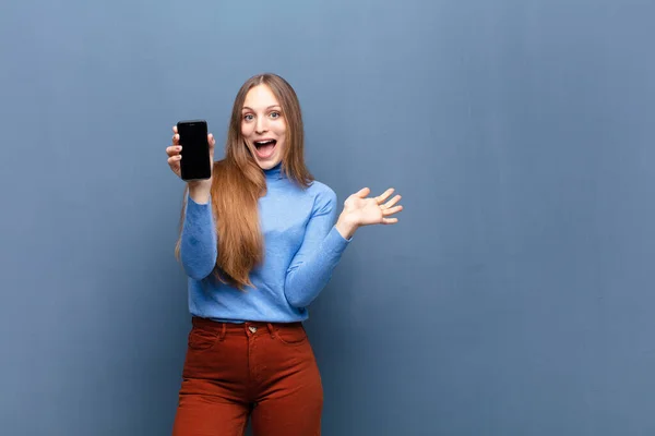 Junge Hübsche Frau Mit Smartphone Gegen Blaue Wand Mit Kopierraum — Stockfoto