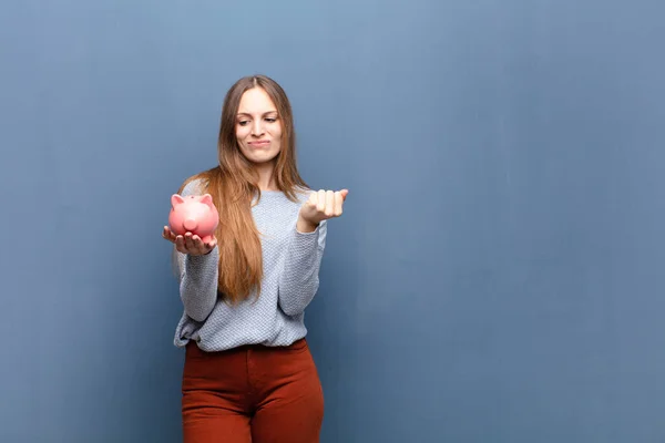 Giovane Bella Donna Con Salvadanaio Contro Muro Blu Con Uno — Foto Stock