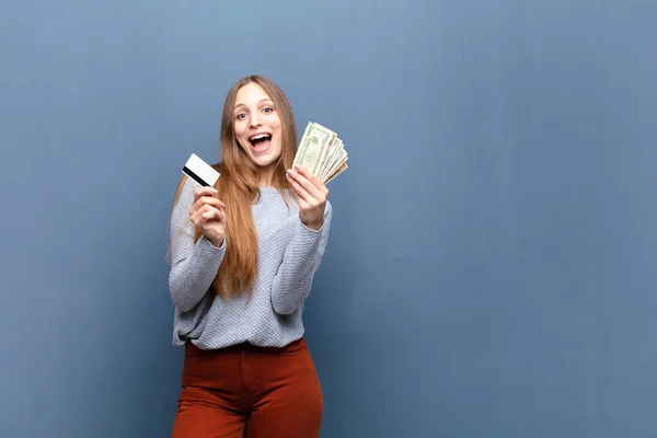 young pretty woman with dollar banknotes against blue wall with a copy space