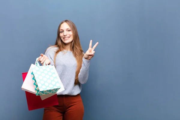 Jonge Mooie Vrouw Met Boodschappentassen Tegen Blauwe Muur Met Een — Stockfoto