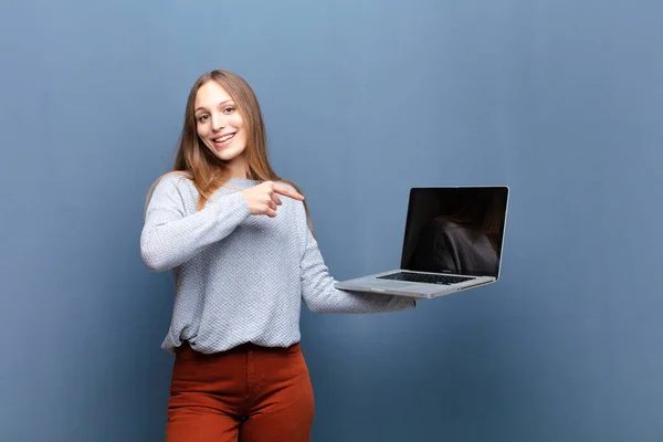 一个年轻漂亮的女人 带着笔记本电脑靠着蓝色的墙壁 有一个复制空间 — 图库照片